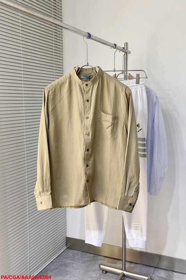 E004 Ada外套衬衫是二零二四夏季男装系列新品，以时尚设计演绎工装美学。采用米色棉质帆布精心制作，搭配同色调标志刺绣和多个贴袋提升格调。可与长裤或休闲短裤轻