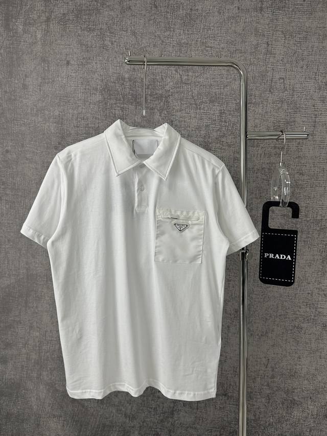 Prada 普拉达2024春夏新款三角标图案贴标休闲翻领男士短袖polo衫 Prada系列融汇传统材质与科技创新面料，塑造混搭设计。这款修身版弹力棉polo衫的